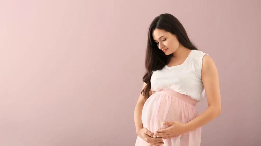 Woman gently holding her pregnant belly during a surrogate pregnancy in California