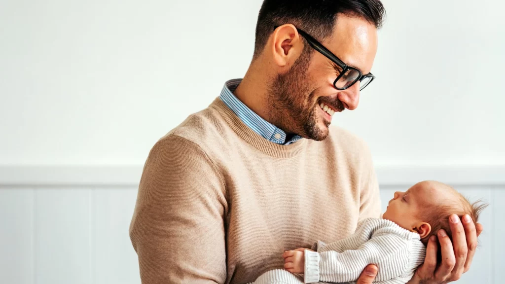 Single father holding newborn baby after surrogacy journey in California